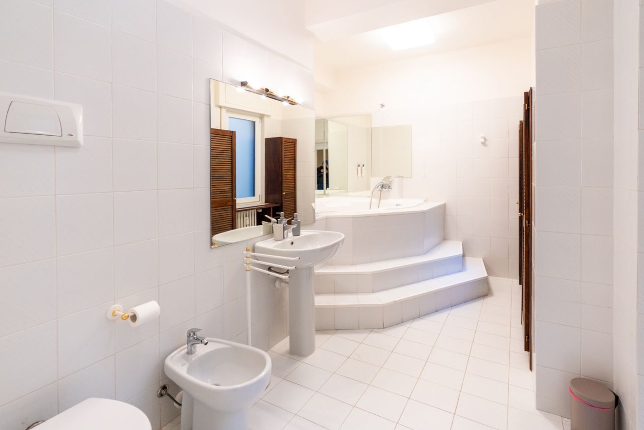 A modern bathroom with a toilet, bidet, sink, and a large bathtub.