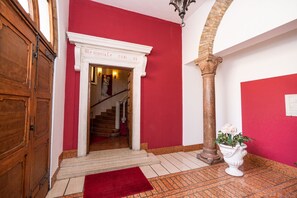Ein Korridor mit roten Wänden, einer weißen Tür, einer Treppe und einer Säule.