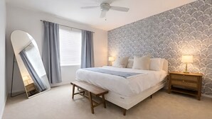 Una camera da letto con un letto, comodini, una ventola a soffitto, una finestra con tende e una parete decorata.