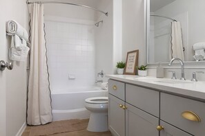 Un baño moderno con bañera, inodoro y tocador con espejo.