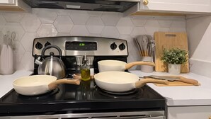 Una cucina con un fornello, pentole, un bollitore e un microonde sopra.
