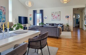 A modern living room with a sofa, dining table, chairs, and artwork on the walls. - Cozy home in Kyrkesund with WiFi (Kyrkesund)