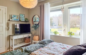 A bedroom with a bed, a TV, a window with a view, and a plant on the windowsill. - Cozy home in Kyrkesund with WiFi (Kyrkesund)