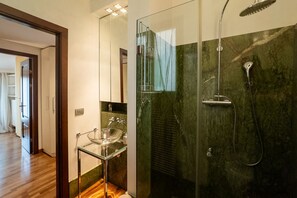 A modern bathroom with a glass-enclosed shower, a glass sink, and a marble wall. - Luxurious residence with large terrace overlooking Arena (Verona)
