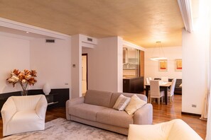 A living room with a sofa, armchair, and a dining area with a table and chairs. - Luxurious residence with large terrace overlooking Arena (Verona)
