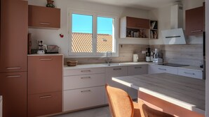 Eine moderne Küche mit Fenster, Schränken und einem Essbereich.