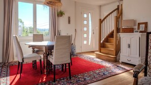 Ein Essbereich mit einem runden Tisch, Stühlen, einem roten Teppich, einer Treppe und einem weißen Schrank.