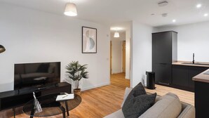 A modern living room with a flat-screen TV, a sofa, a coffee table, and a potted plant. - City Point Aberdeen by Guestz (Aberdeen)