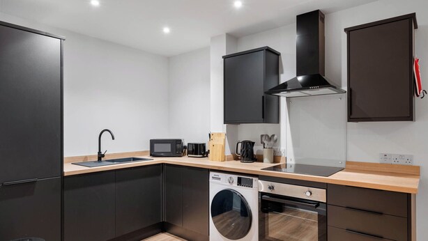 A modern kitchen with a sink, microwave, stove, and washing machine. - City Point Aberdeen by Guestz (Aberdeen)