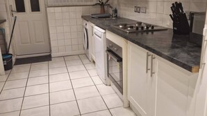 Una cocina moderna con armarios blancos, un lavamanos, una estufa y un lavavajillas.