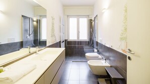 A modern bathroom with a large mirror, two sinks, a bathtub, and a toilet. - Cozy and central Vicolo Stella residence (Verona)