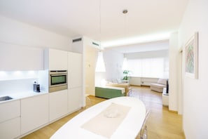 Eine moderne Küche mit weißen Schränken, einem eingebauten Backofen und einem Essbereich mit weißem Tisch und Stühlen.