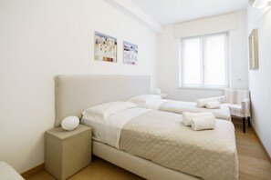 Quarto de hotel com duas camas, uma janela e obras de arte na parede.