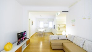 A modern living room with a sofa, TV, and a dining area with a table and chairs. - Cozy and central Vicolo Stella residence (Verona)