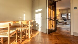 A dining area with wooden furniture, a kitchen with white cabinets, and a view of a living room through an open door. - South Castle Street | St Andrews (St Andrews)