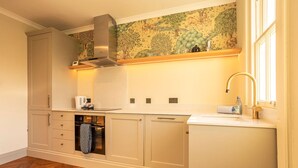 A kitchen with a herringbone floor, a built-in oven, and a stainless steel range hood. - South Castle Street | St Andrews (St Andrews)