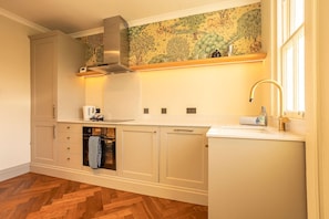 A kitchen with a herringbone floor, a built-in oven, and a stainless steel range hood. - South Castle Street | St Andrews (St Andrews)