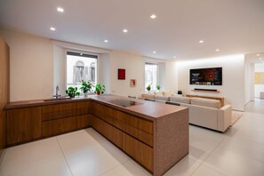 Eine moderne Küche mit einer großen Kochinsel, integrierten Schränken und einem Essbereich mit einer Couch.