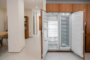 A modern kitchen with a built-in refrigerator, wooden cabinets, and a tiled floor. - Modern and luxurious residence in the center of Verona (Verona)