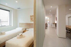 Ein Hotelzimmer mit zwei Betten, einem großen Fenster, einem Schreibtisch und einem Stuhl.
