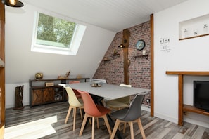 Ein Essbereich mit Backsteinwand, einem Dachfenster und einem Kamin.