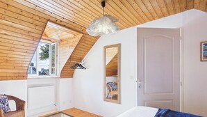 A bedroom with a sloped ceiling, a bed, a hanging light fixture, a mirror, and a window. - ROCA - Charming farmhouse (La Forêt-Fouesnant)