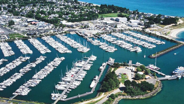 An aerial view of a marina with numerous boats docked in a grid pattern, surrounded by residential buildings and a small pier with a boat. - ROCA - Charming farmhouse (La Forêt-Fouesnant)