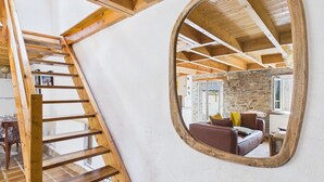 A loft bedroom with a wooden ladder, a large mirror, and a stone wall. - ROCA - Charming farmhouse (La Forêt-Fouesnant)