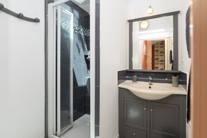 A bathroom with a shower, sink, and mirror. - Cottage "Le Nid de Tristan et Iseut" with Private Terrace, Garden, and Wi-Fi (Plumelin)