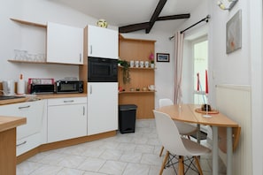 A compact kitchen with white cabinets, a microwave, and a small dining area with a table and chairs.