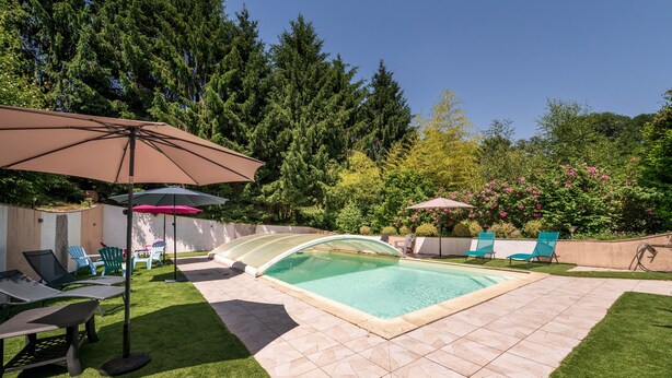 Ein Garten mit Swimmingpool, Rasen und Gartenmöbeln.