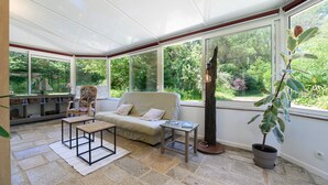 Ein Wintergarten mit Sofa, Couchtisch und Topfpflanze.