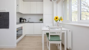 Eine moderne Küche mit weißen Schränken, einem eingebauten Backofen und einem Essbereich mit einem weißen Tisch und Stühlen.