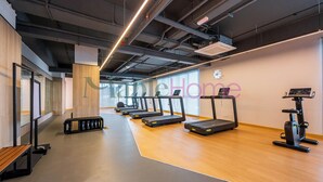 Un gimnasio con cintas de correr, una bicicleta estática y un banco.