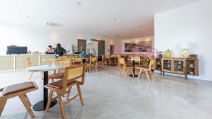 Un restaurante moderno con mobiliario de madera, una barra y un cuadro grande en la pared.