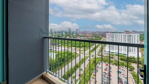 Un balcón con vista a un paisaje urbano, que incluye calles, áreas verdes y edificios.