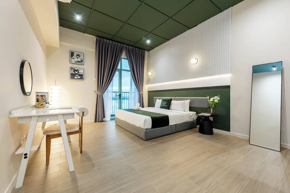 A modern hotel room with a bed, desk, chair, and a large window with curtains.