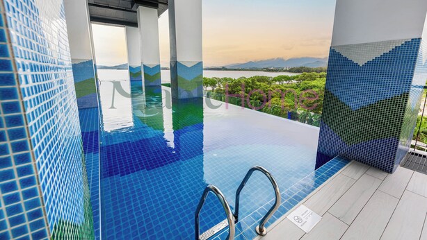Una piscina infinita con vista a un lago y montañas, rodeada de paredes con azulejos.