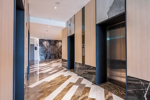 A modern hallway with a marble floor, wooden walls, and an elevator. - Bay Suites Premier Suites Kota Kinabalu (Kota Kinabalu)