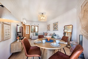 A dining area with a round table, brown leather chairs, a central light fixture, and a wall-mounted mirror. - Terra o do Sol Tavira (Tavira)