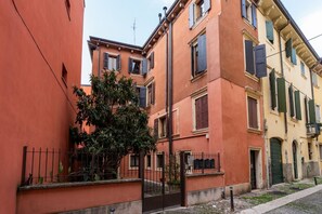A narrow street with buildings featuring traditional architecture, a metal gate, and a tree. - Elegant and modern residence in the heart of Verona (Verona)