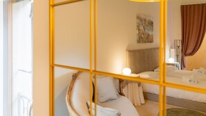 Ein Hotelzimmer mit Bett, Sessel, Lampe und einem Bild an der Wand.