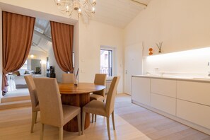A modern kitchen with white cabinets, a wooden dining table, and beige chairs. - Elegant and modern residence in the heart of Verona (Verona)