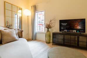 A hotel room with a bed, a large mirror, a TV, a vase with dried plants, and a window with curtains. - Elegant and modern residence in the heart of Verona (Verona)