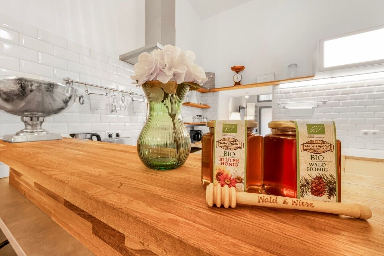A kitchen counter with a vase, honey jars, and a honey dipper.