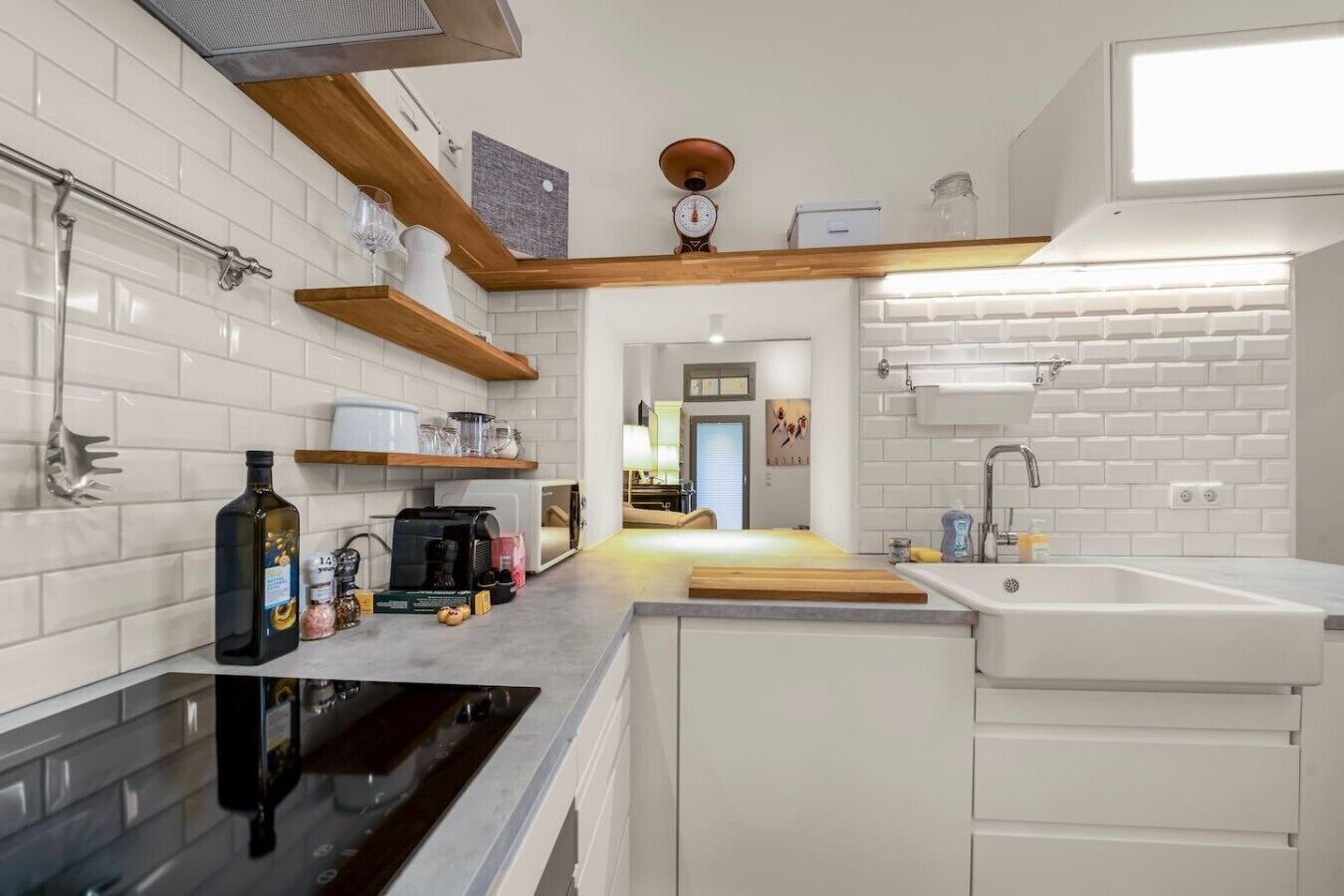 A modern kitchen with white subway tiles, a black stove, and wooden shelves.