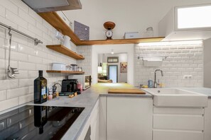 Een moderne keuken met witte metrotegels, een zwarte kookplaat en houten planken.