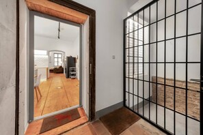 A room with a wooden floor, a white door, and a view of a living area with a sofa and a table. - 1 BR Apartment in Neubau, 8 min city center, AC (Wien)