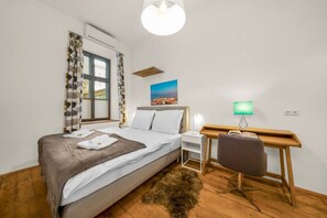 A hotel room with a bed, a desk, a chair, a lamp, and a painting on the wall. - 1 BR Apartment in Neubau, 8 min city center, AC (Wien)