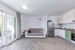 A modern apartment with a kitchenette, a sofa, and a dining area. - Wabi Sabi Apartments With Pool (Krk)
